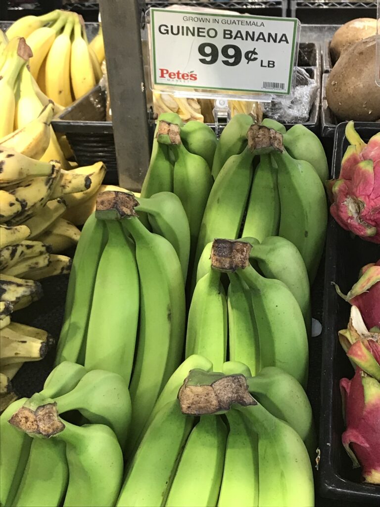 Photos of several green bunches of bananas next to a sign that reads "Guineo Banans / Grown in Guatemala / 99 cents lb"