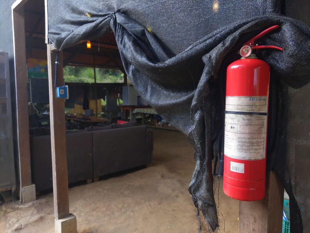 Photo of a large red fire extinguisher attached to a wooden post on the side of a building