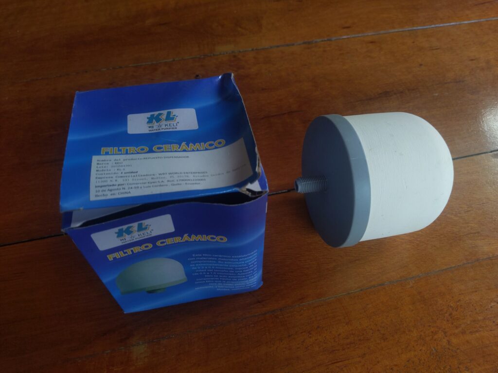 Photo of a box with "Filtro Ceramico" written on it. There is a small ceramic water filter next to the box.