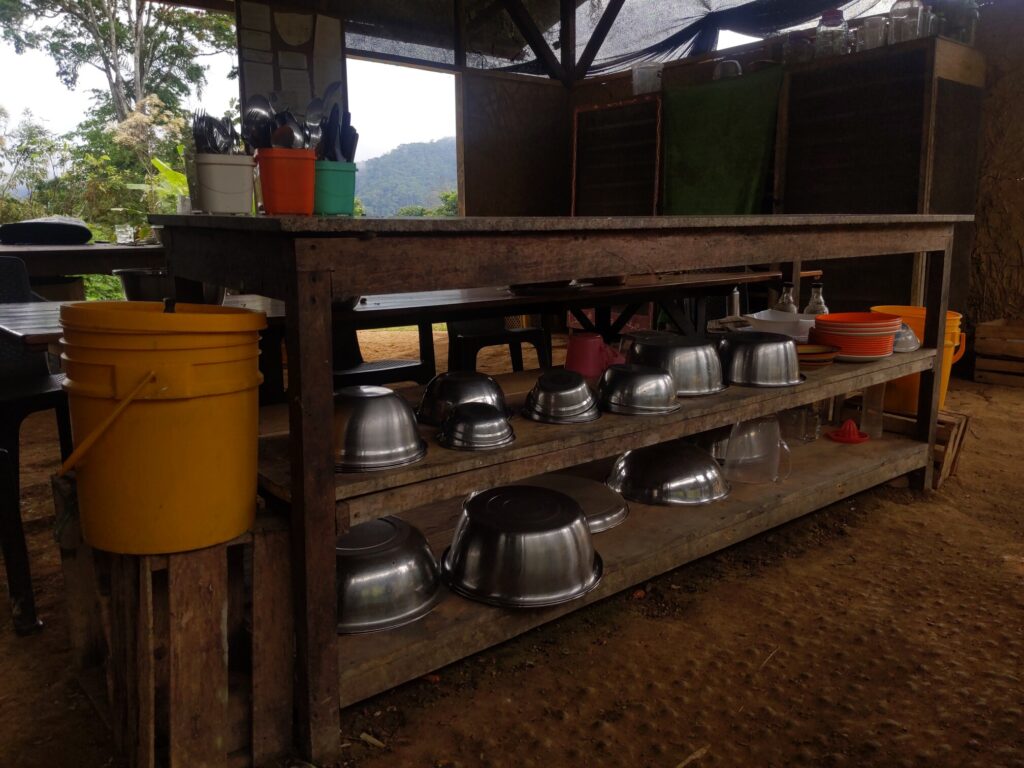 Photo of a very large food-preparation counter with shelfs containing dozens of large steel bowls