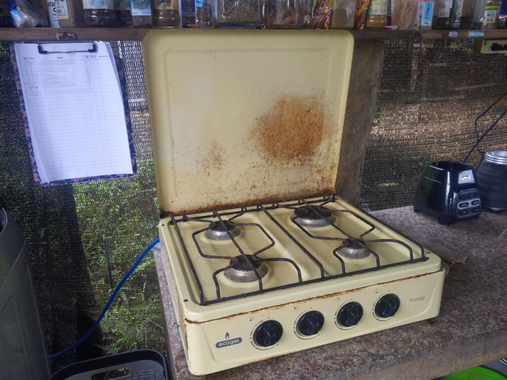 Photo of a 4-burner gas stove with a blue gas pipe coming out of it.